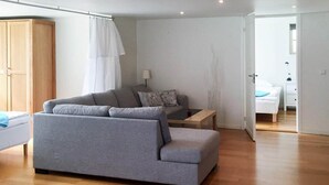A modern living room with a grey sofa, a wooden coffee table, and a white lamp. - Holiday Home in Lysekil (Lysekil)