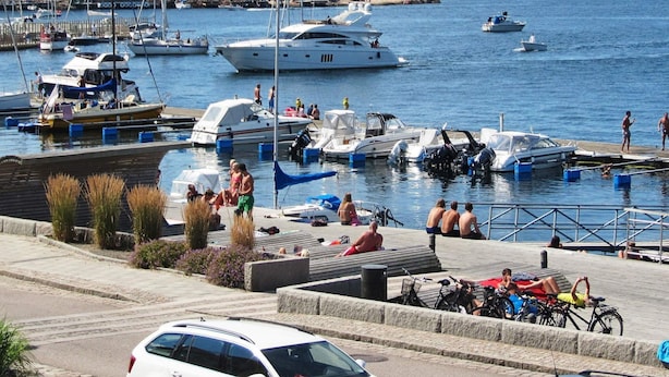 A marina with boats docked, people relaxing, and a car in the foreground. - Holiday Home in Lysekil (Lysekil)