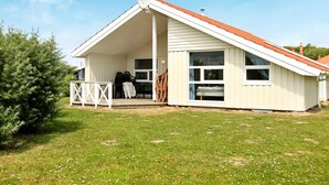 A single-story house with a sloped roof, a covered porch, and a large window. - Holiday Home in Otterndorf (Otterndorf)