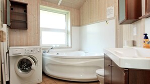 A compact bathroom with a washing machine, a bathtub, and a toilet. - Holiday Home in Otterndorf (Otterndorf)