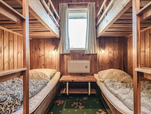 A cabin with two bunk beds, a small table, and a window with curtains.