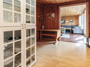 A wooden interior with a kitchen area, a dining table, and a living room with a sofa.