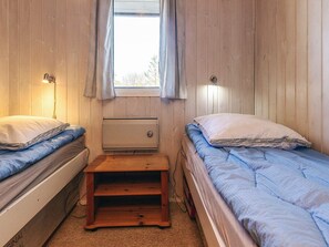 A small room with two beds, a window with curtains, a heater, and a wooden stool. - 10 Person Holiday Home in Lokken-by Traum (Lokken)