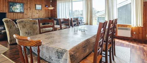 Un comedor con una mesa grande, sillas de madera y un techo con vigas de madera.