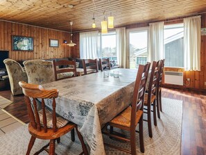 Une salle à manger avec une grande table, des chaises en bois et un plafond orné de poutres en bois.