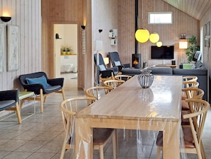 Un amplio espacio de sala con una larga mesa de madera, varias sillas, un sofá y una chimenea.