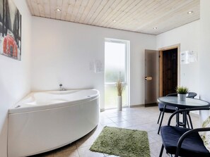 Un baño moderno con una bañera independiente, una cabina de ducha con paredes de vidrio y un comedor con una mesa redonda y sillas.