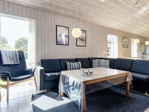 Una sala moderna con un sofá seccional, una mesa de comedor y vistas al exterior.