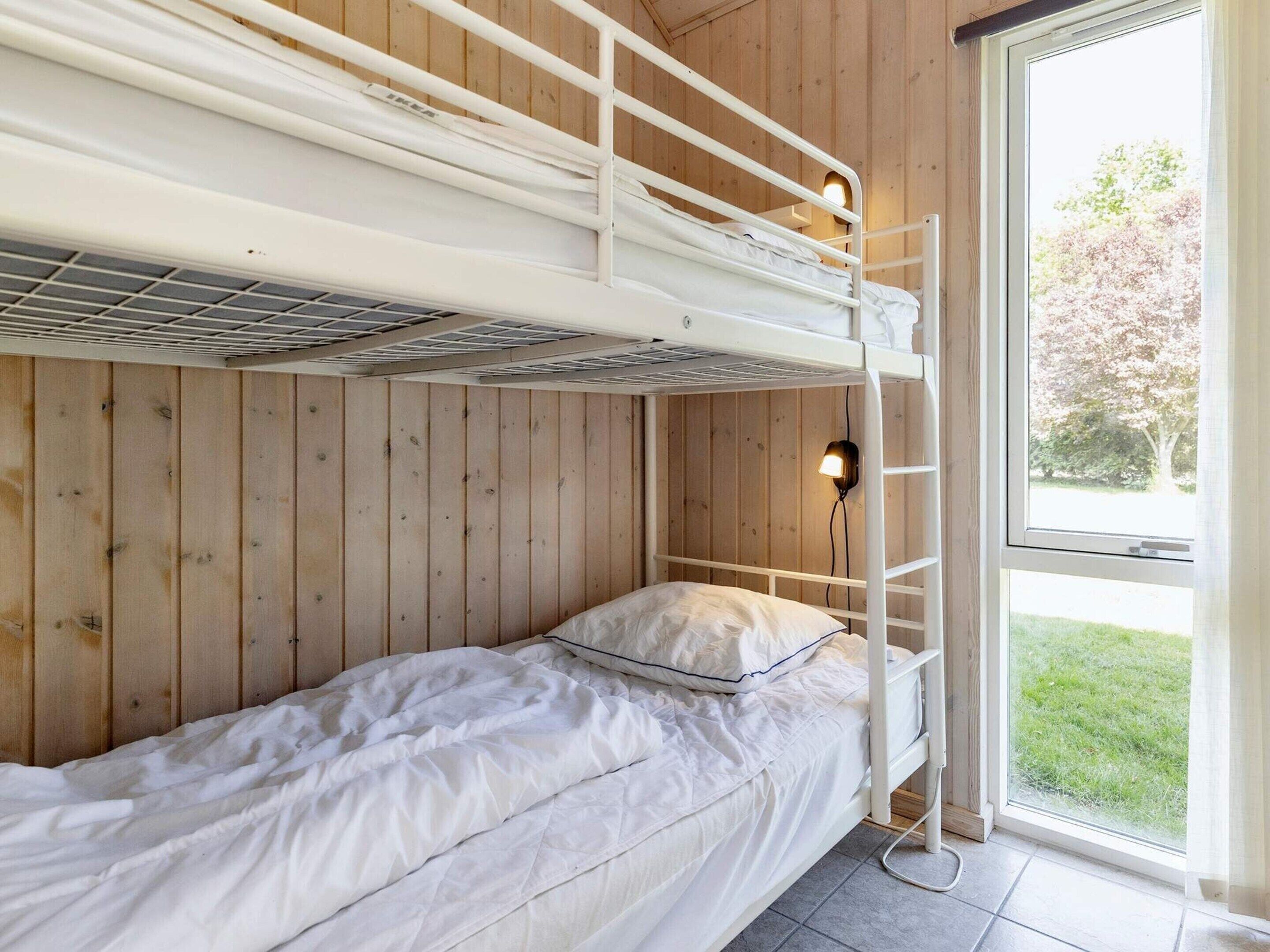 A bunk bed room with a wooden wall and a window.