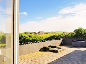 A wooden deck with a view of a rural landscape, including houses and greenery.