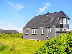A two-story house with a dark grey exterior, a sloped roof, and a small attached garage.