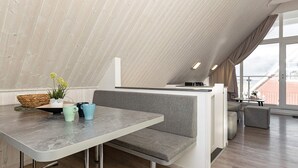 Une pièce moderne de style loft, dotée d’un haut plafond, d’un coin repas avec un banc et d’un espace cuisine avec un comptoir.
