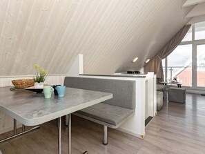 Une pièce moderne de style loft, dotée d’un haut plafond, d’un coin repas avec un banc et d’un espace cuisine avec un comptoir.