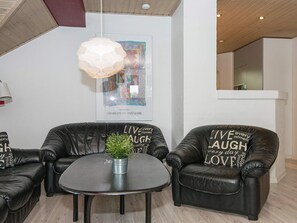 A room with two black leather sofas, a small round table with a plant, and a ceiling light fixture. - 4 Star Holiday Home in Juelsminde (Horsens)