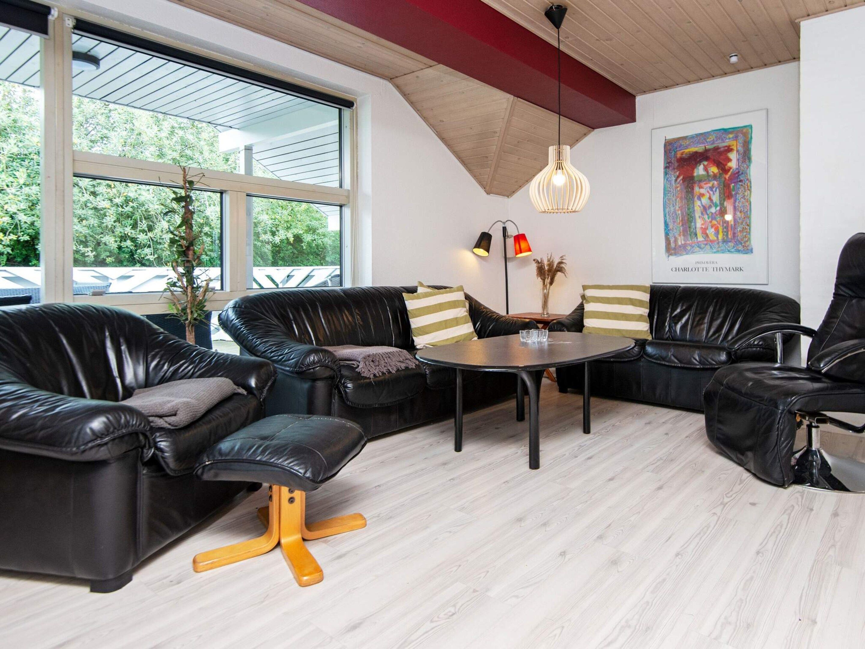 A modern lounge area with leather sofas, a round table, and a pendant light.