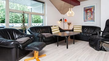 A modern lounge area with leather sofas, a round table, and a pendant light.