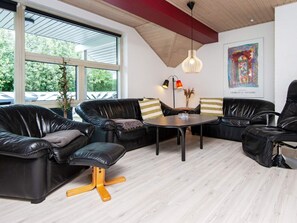 A modern lounge area with leather sofas, a round table, and a pendant light. - 4 Star Holiday Home in Juelsminde (Horsens)