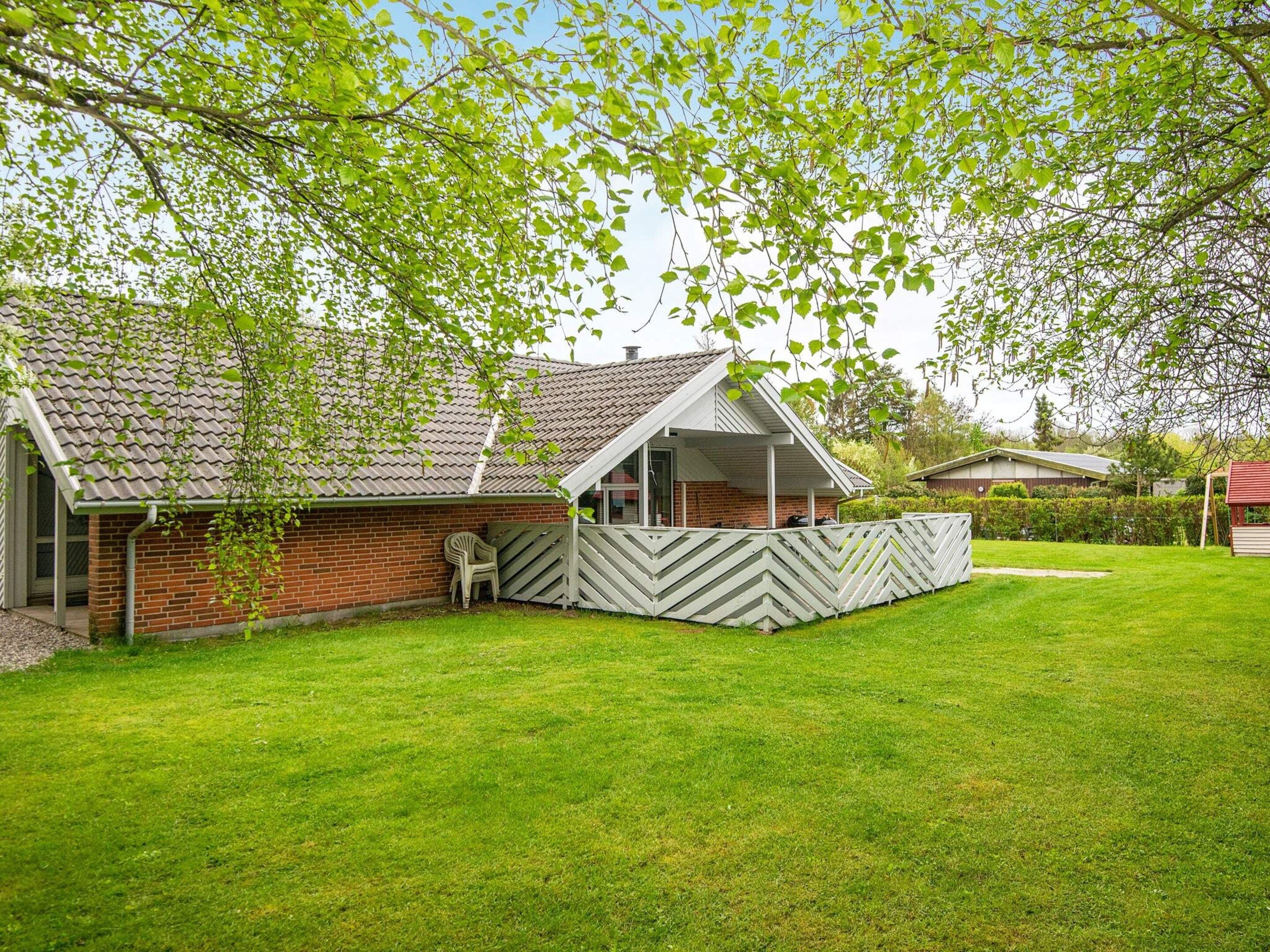 A brick house with a covered porch and a fenced yard.