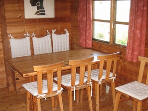 A wooden dining table with six chairs, each with a white cushion and tied with a white ribbon. - 6 Person Holiday Home in Hirtshals (Hirtshals)