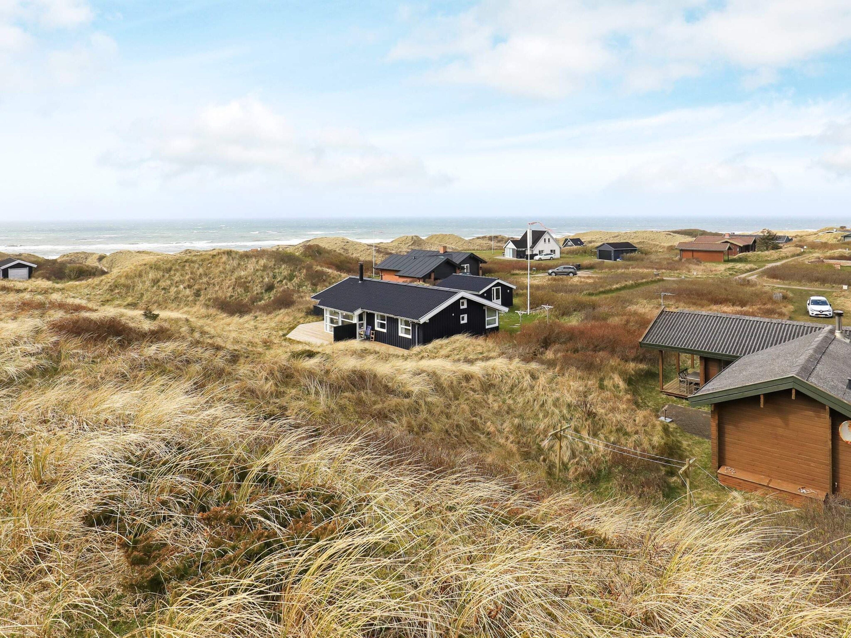 A coastal property with multiple houses surrounded by dunes and the sea.