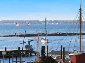 A marina with boats docked, a wooden pier, and a red building.