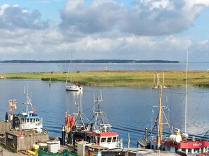 A harbor with various boats, including a sailboat and fishing vessels, docked alongside.