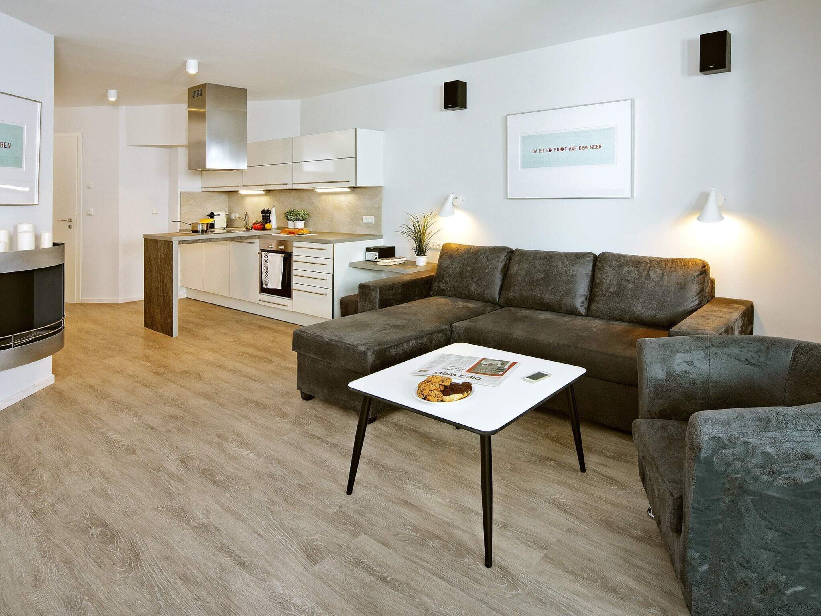 A modern living room with a sectional sofa, a coffee table, and a kitchen in the background.