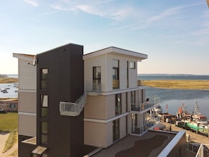 Ein modernes, mehrgeschossiges Gebäude mit Balkon in der Nähe von Wasser und Booten.