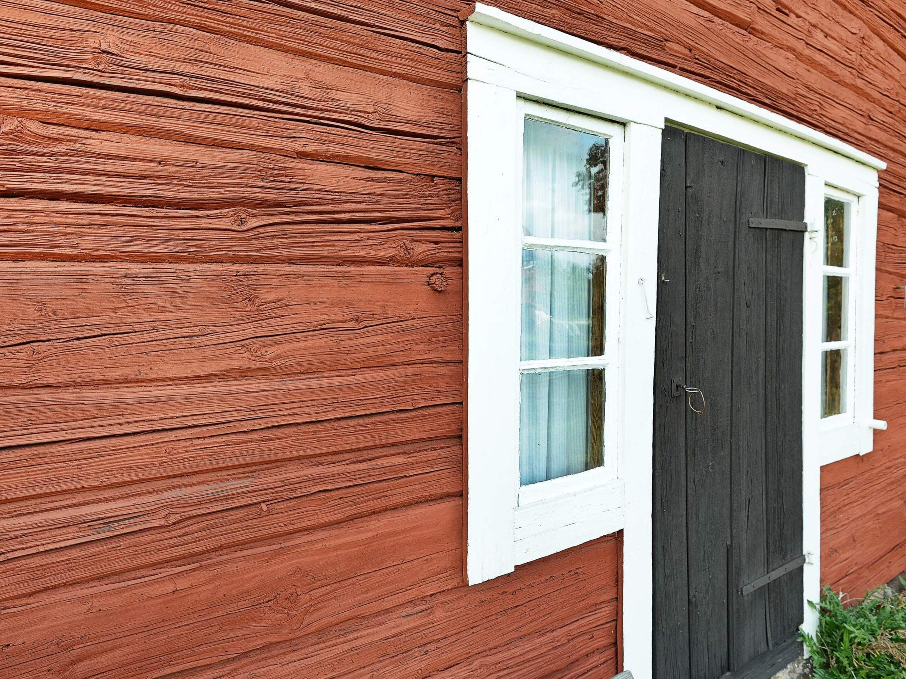 A wooden building with a white window and a dark door.