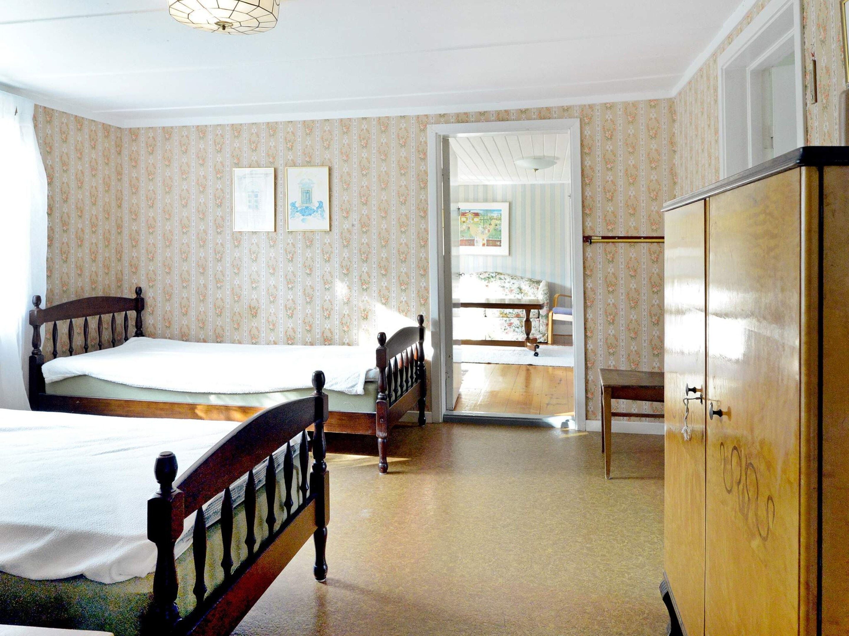 A bedroom with two beds, a wardrobe, and a door leading to a bathroom.