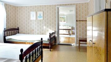 A bedroom with two beds, a wardrobe, and a door leading to a bathroom.