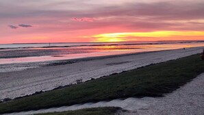 En strand med en vacker solnedgång, ett grönområde och en stig.