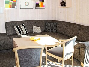 A modern living room with a sectional sofa, a small table, and two chairs. - Holiday Home in Otterndorf (Otterndorf)