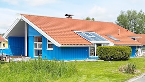 A blue house with a red roof, a covered porch, and a small garden. - Holiday Home in Otterndorf (Otterndorf)