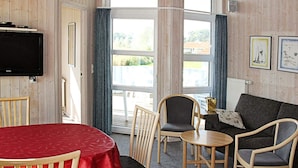 A room with a television, a red table, and a sofa with a cushion. - Holiday Home in Otterndorf (Otterndorf)