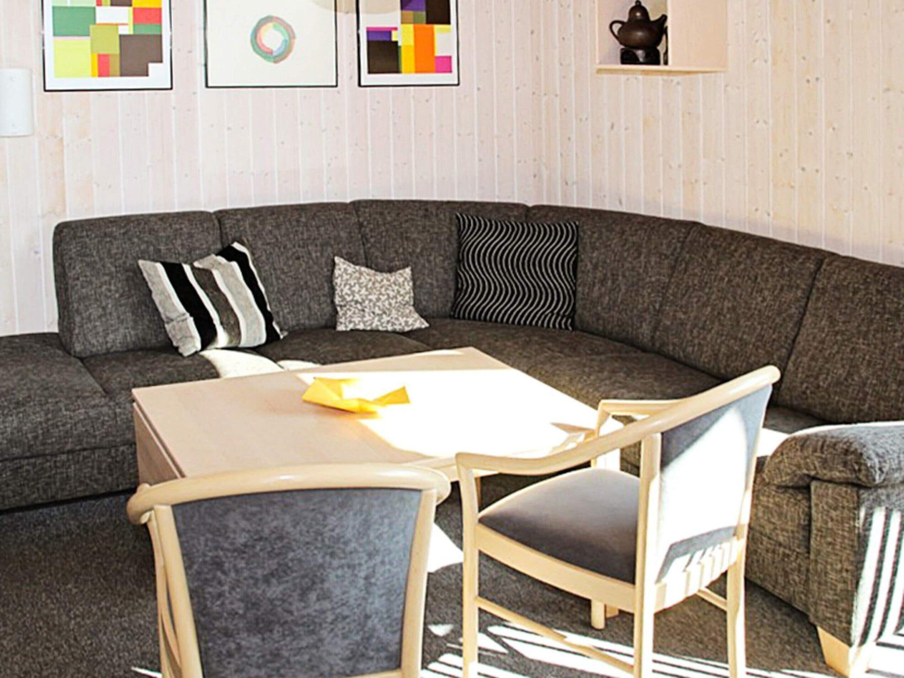 A modern living room with a sectional sofa, a small table, and two chairs.
