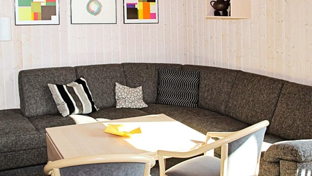 A modern living room with a sectional sofa, a small table, and two chairs. - Holiday Home in Otterndorf (Otterndorf)