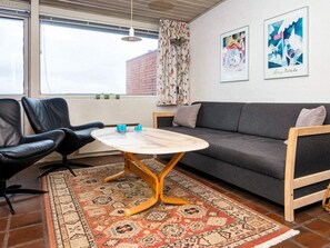 A modern living room with a sofa, a coffee table, and a patterned rug. - Waterfront Holiday Home in Henne near Sea (Henne)