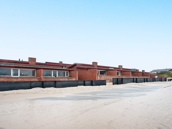 A row of brick houses with a sandy ground in front.