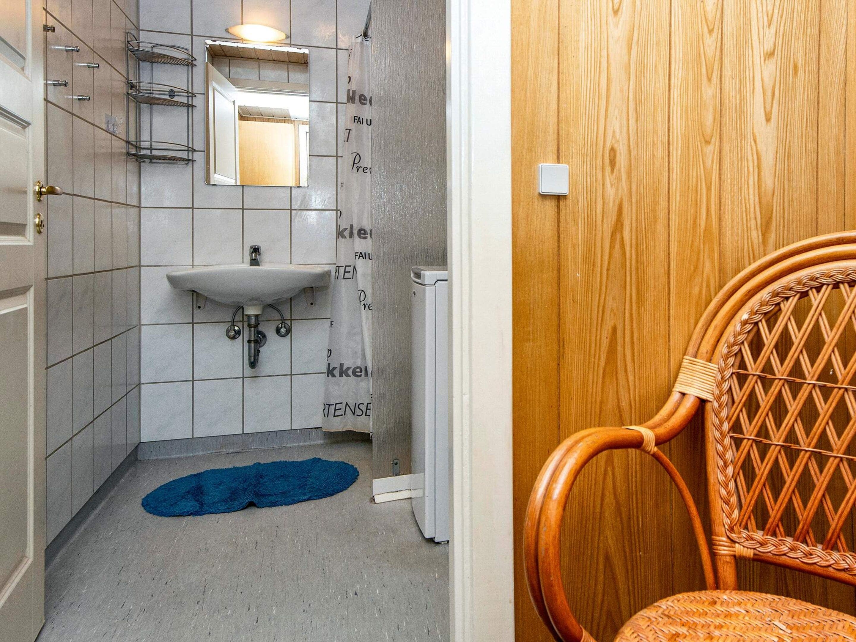 A bathroom with a white sink, a mirror, a towel rack, and a blue rug.