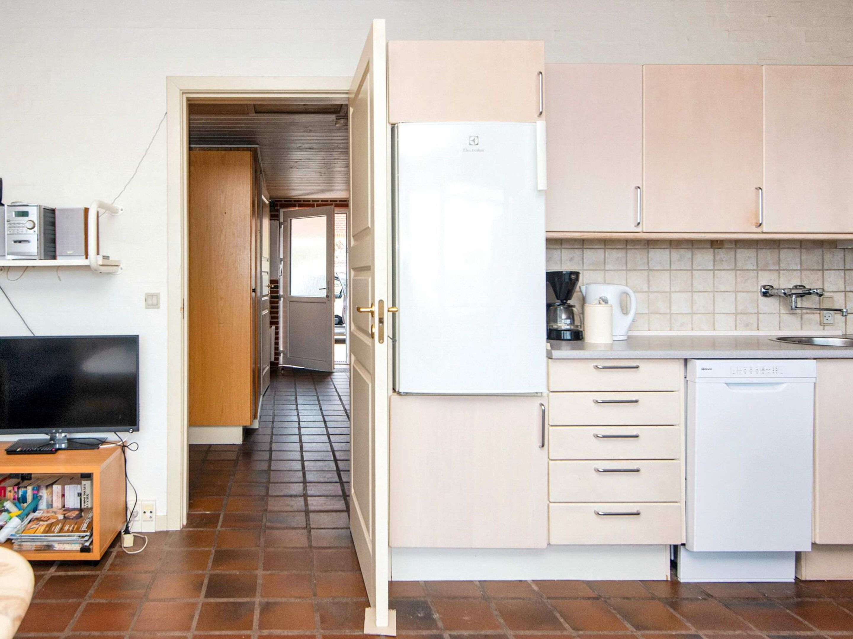 Een kleine keuken met een koelkast, een koffiezetapparaat en een vaatwasser.
