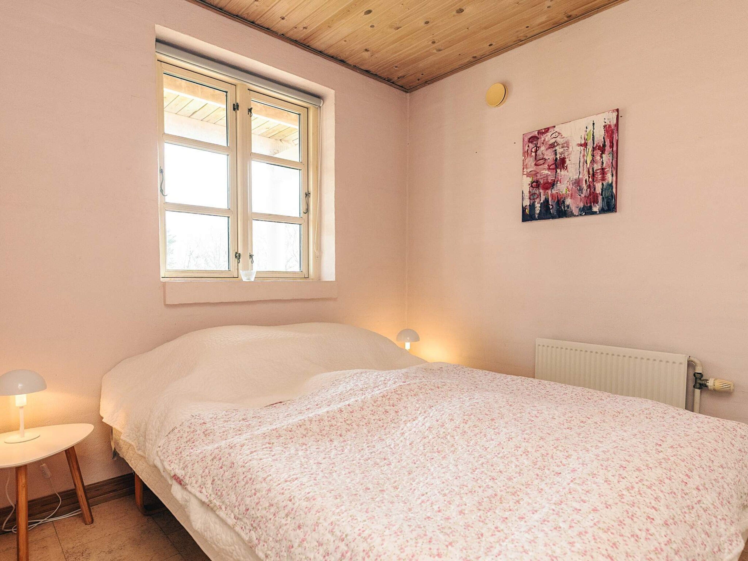 Une chambre à coucher avec un lit, une fenêtre, un radiateur et un tableau accroché au mur.