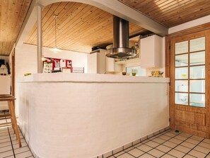 Een keuken met een houten plafond, een centraal eiland en uitzicht buiten door een raam.