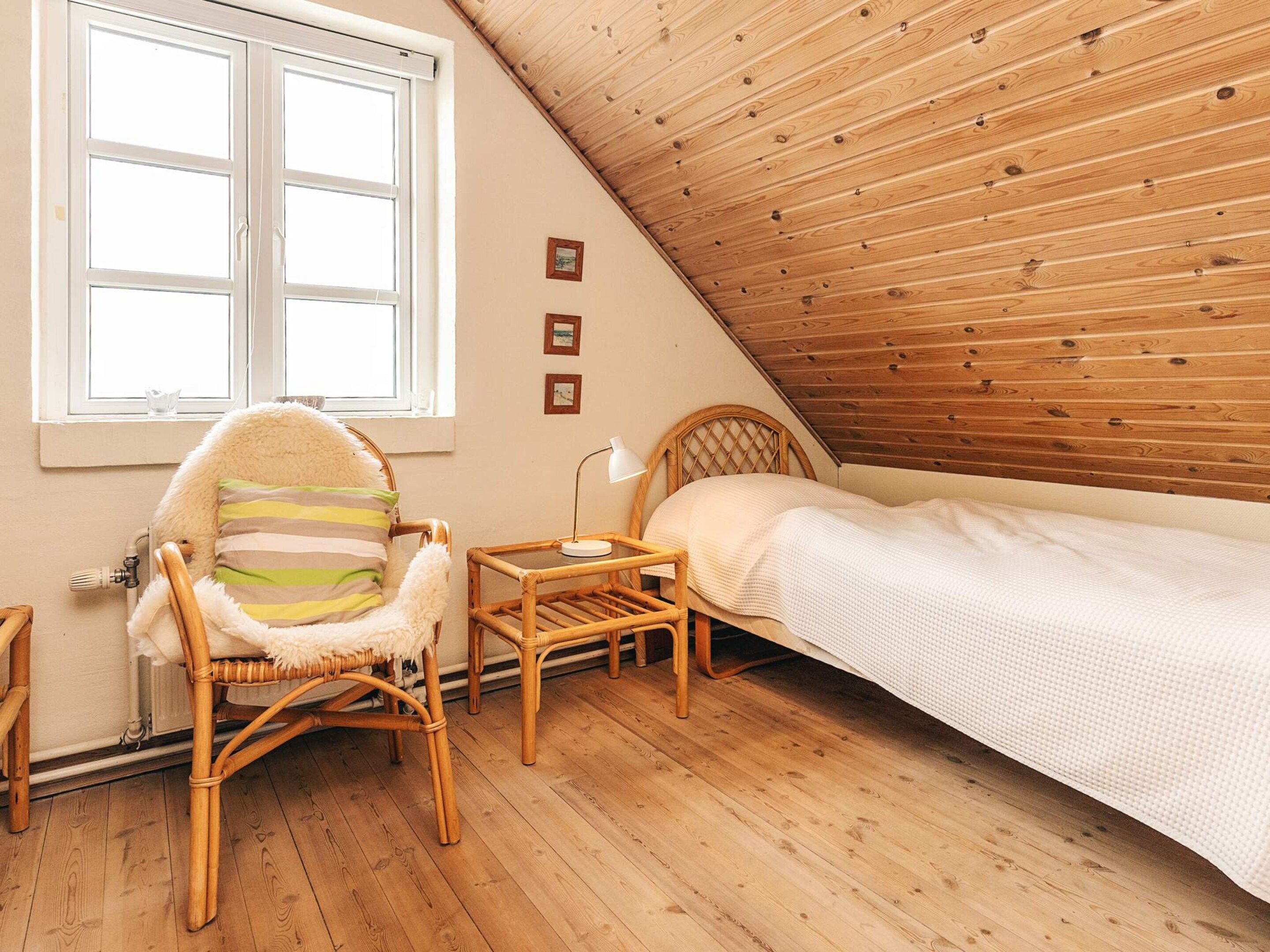 Une pièce confortable avec un plafond en pente, un lit, une chaise et une petite table.