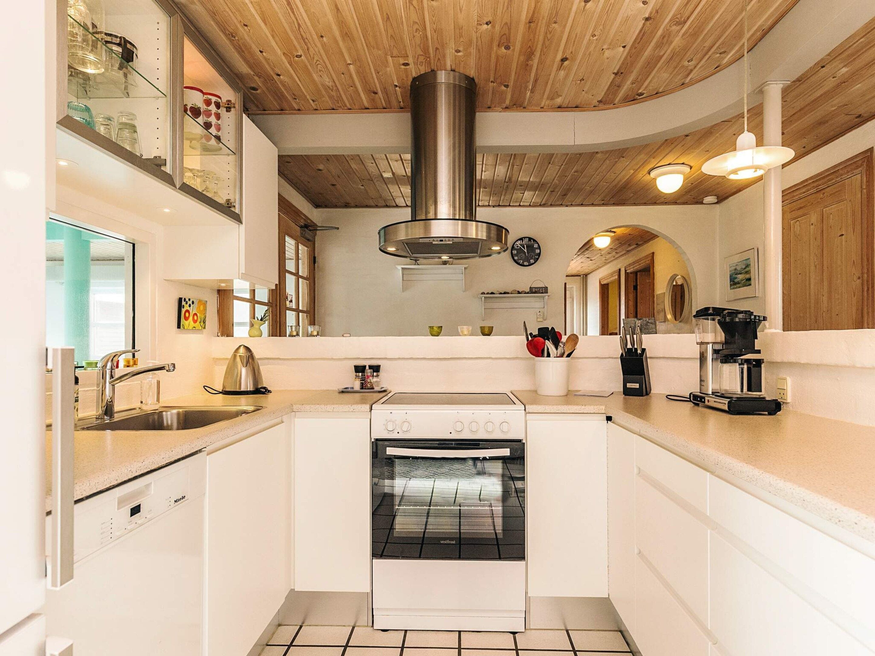 A modern kitchen with a built-in oven, stainless steel range hood, and a coffee machine.