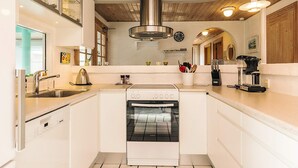 A modern kitchen with a built-in oven, stainless steel range hood, and a coffee machine. - 4 Star Holiday Home in Fur (Fur)