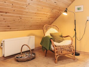 A cozy room with a sloped ceiling, a wicker chair with a cushion, a floor lamp, and a radiator. - 4 Star Holiday Home in Fur (Fur)