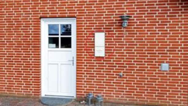 A red brick building with a white door, a small window, and a mailbox. - 4 Star Holiday Home in Fur (Fur)