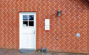 A red brick building with a white door, a small window, and a mailbox. - 4 Star Holiday Home in Fur (Fur)