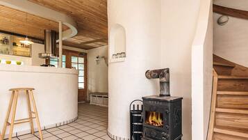 Una cocina con una isla central, un taburete de madera, una estufa y una pared de ladrillo blanco.